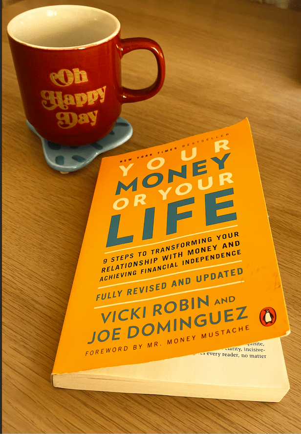 het boek your money or your life van Vicki Robin en Joe dominguez met daarbij een rode tas waarop o happy day staat